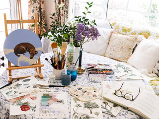 art studio desk covered in paintings and inspiration, colour swatches in a light filled studio.