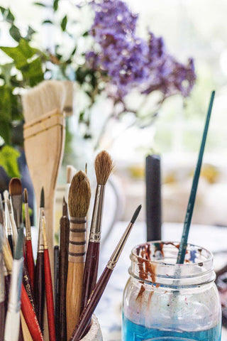 paint brushes and flowers in a jar