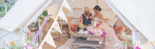 bride and grrom sitting in a tent with bunting and flowers
