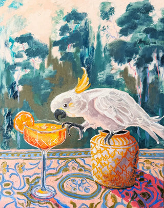 A cheeky still life painting. A colourful painting of a white cockatoo perched on a patterned table next to an orange cocktail glass and a decorative vase, with a painted Australian forest background.