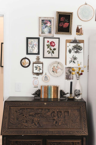 timber Chinese carved desk with floral gallery wall and vintage books