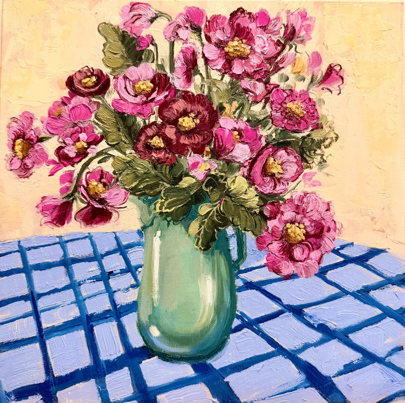 A colorful still life painting of a bouquet of pink and burgundy flowers in a mint green jug, set on a blue checkered table against a warm butter yellow background.