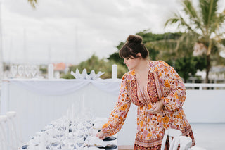 woman in orange dress setting a coastal wedding table
